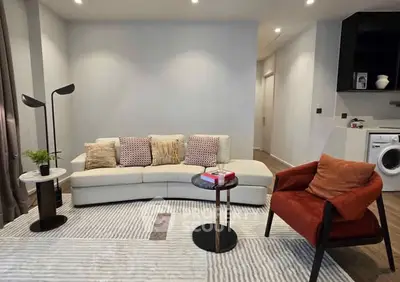 Modern living room with stylish furniture and washing machine in open layout.