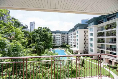 Luxurious apartment balcony with stunning pool and garden view in modern residential complex.