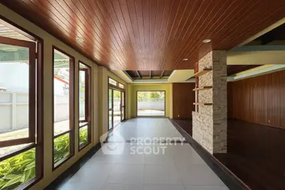 Spacious modern living room with wooden ceiling and large windows offering natural light.