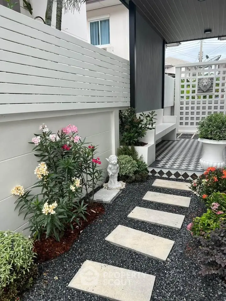 Charming garden pathway with lush greenery and decorative elements in a modern residential setting.