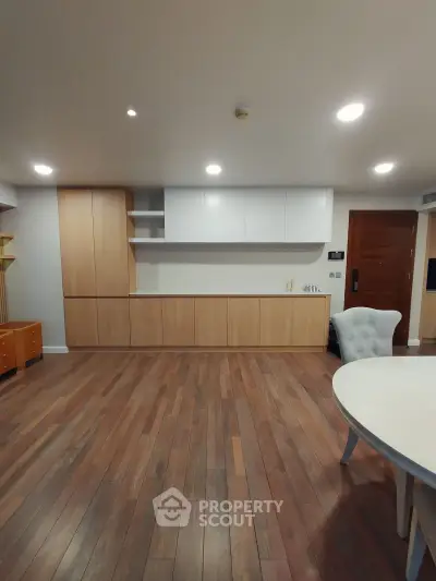 Spacious modern living room with wooden flooring and built-in storage cabinets.