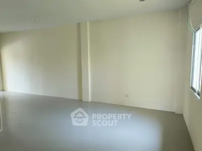 Spacious empty room with large window and neutral walls, perfect for customization.
