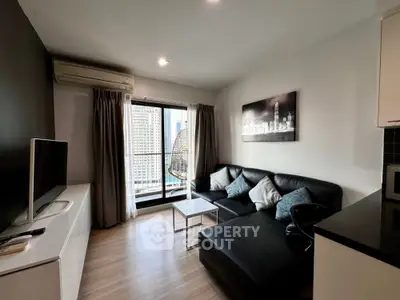 Modern living room with city view, stylish black sofa, and wall art in a high-rise apartment.
