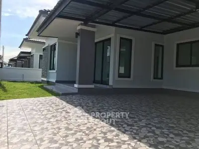 Modern single-story house with spacious tiled patio and large windows.