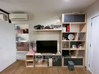 Modern living room with stylish shelving and TV unit, adjacent to a sleek kitchen area.