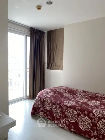 Cozy bedroom with large window and stylish red patterned bedspread