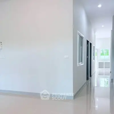 Spacious modern hallway with glossy tiled floors and bright natural lighting.