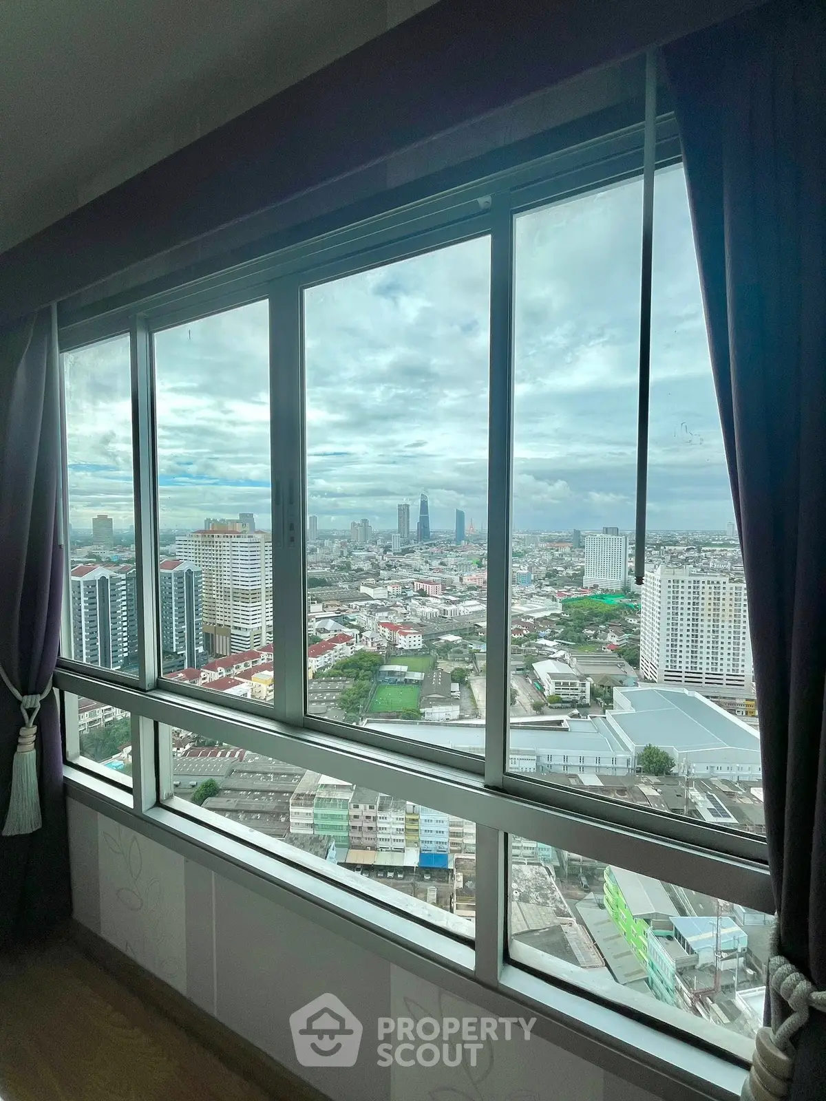Stunning cityscape view from high-rise apartment window with expansive skyline.