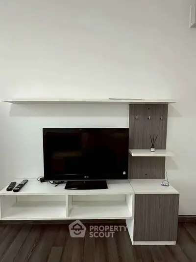 Modern living room with sleek TV stand and flat-screen TV on wooden flooring.