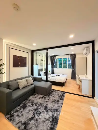 Modern studio apartment with stylish living area and cozy bedroom, featuring large windows and elegant decor.