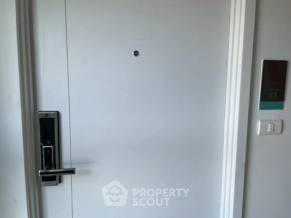Modern apartment door with electronic lock and room number, showcasing secure entry features.