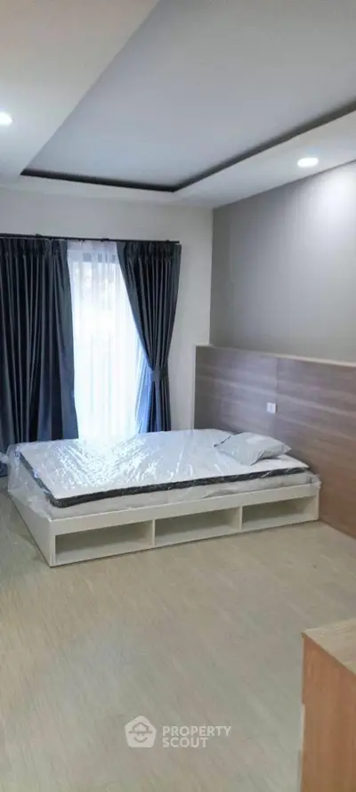 Modern bedroom with sleek design and natural light, featuring a stylish bed and elegant curtains.