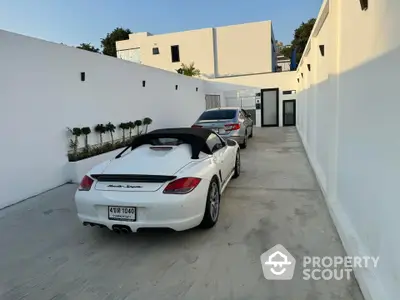 Modern driveway with luxury cars leading to a stylish contemporary home