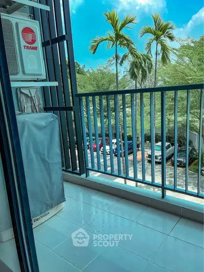 Charming balcony with serene view of palm trees and parked cars, perfect for relaxation.
