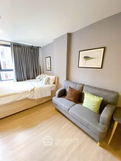 Modern studio apartment with cozy bed and stylish sofa in bright, airy space.