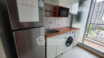Modern kitchen with sleek appliances and balcony view in urban apartment.