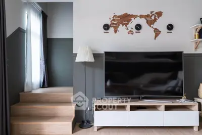 Modern living room with stylish decor and large flat-screen TV, featuring a world map wall art and sleek furniture.