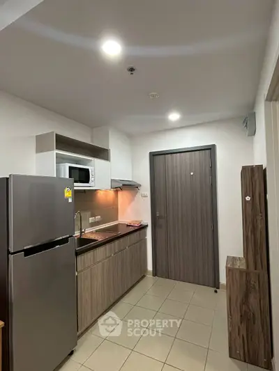 Modern compact kitchen with stainless steel appliances and wood cabinetry