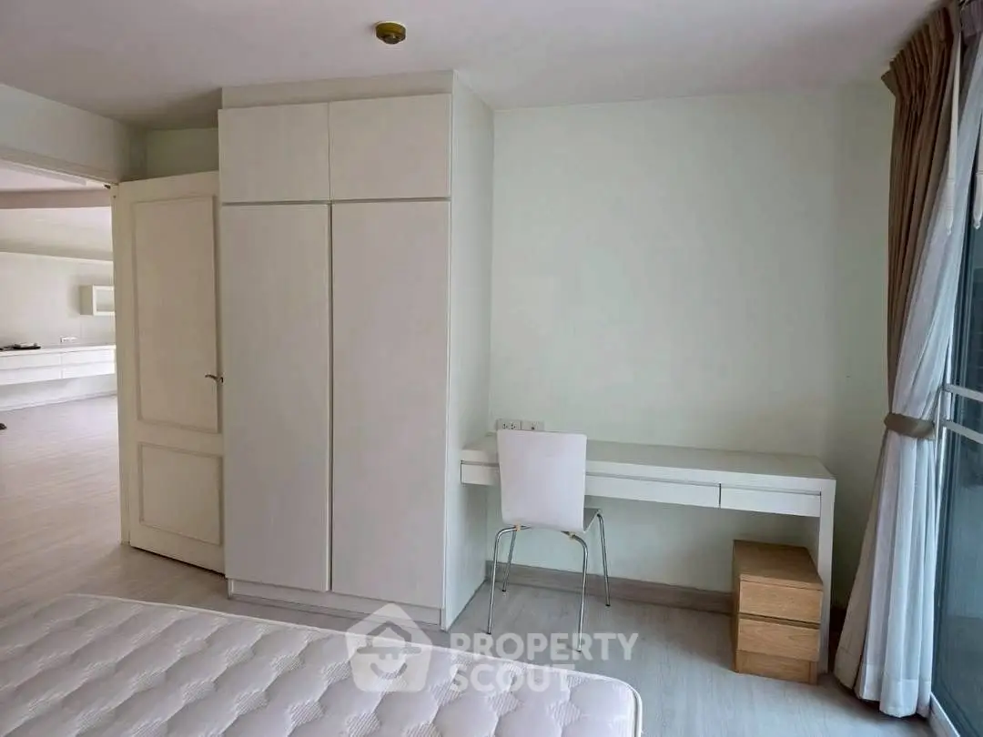 Spacious bedroom with modern furniture and large window for natural light.