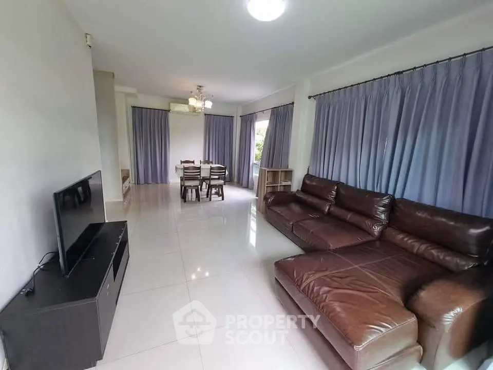 Spacious living room with leather sofa and dining area, perfect for family gatherings.
