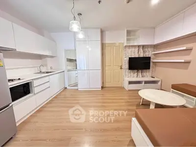 Modern living room with open kitchen, sleek white cabinets, and cozy seating area.