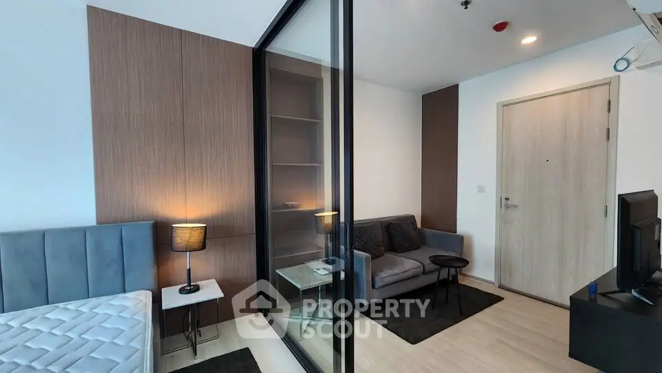 Modern apartment interior with glass partition, cozy living area, and stylish decor.
