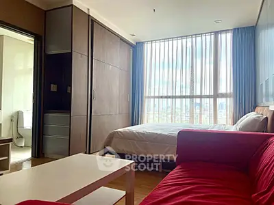 Modern bedroom with large window, cozy red sofa, and sleek built-in wardrobe.