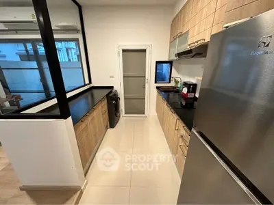 Modern kitchen with sleek appliances and closed layout, featuring a washing machine and stainless steel fridge.