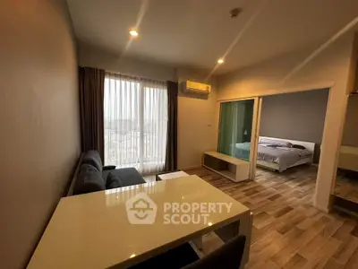 Modern living room with dining area and view into cozy bedroom