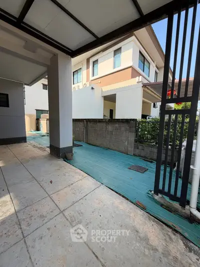 Modern residential building exterior with spacious driveway and garden area.
