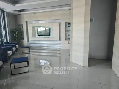 Modern lobby with sleek design and polished tile flooring, featuring a wall-mounted TV and stylish seating area.