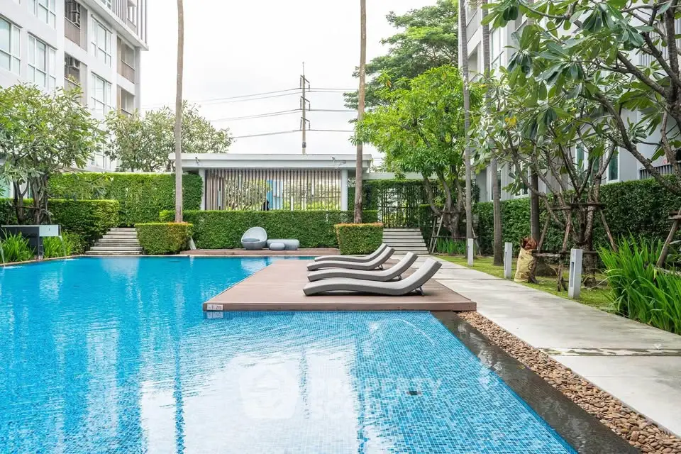 Luxurious poolside area with modern design and lush greenery in a high-end residential complex.