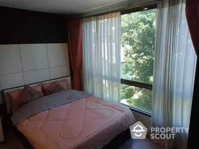 Cozy bedroom with large windows offering ample natural light and a serene tree-lined view, perfect for relaxation and tranquility in a modern home.