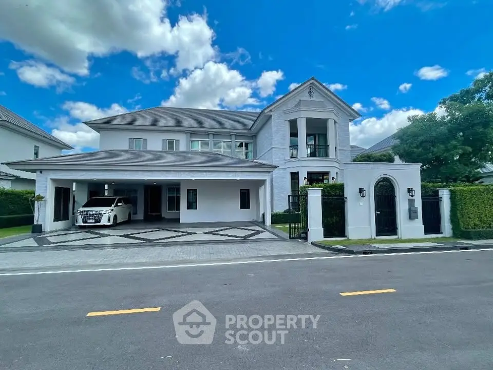 Luxurious two-story house with elegant driveway and lush greenery under a clear blue sky.