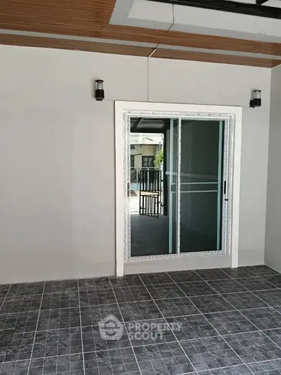 Modern patio with sliding glass door and tiled flooring, perfect for outdoor relaxation.