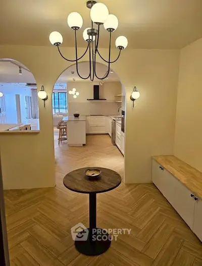 Charming open-layout kitchen with elegant lighting and cozy dining area, perfect for modern living.