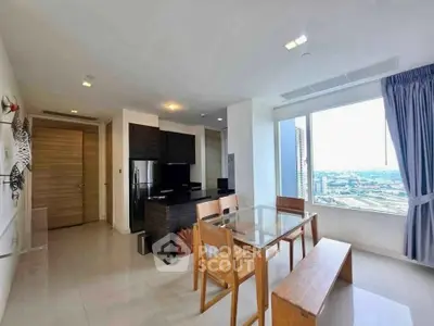 Modern living room with dining area and city view, featuring sleek furniture and large windows.