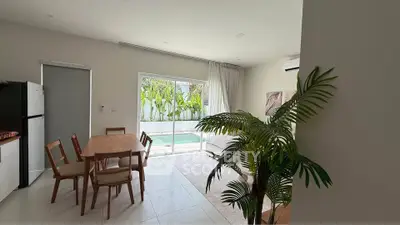 Bright dining area with pool view, modern furniture, and lush greenery for a serene living experience.