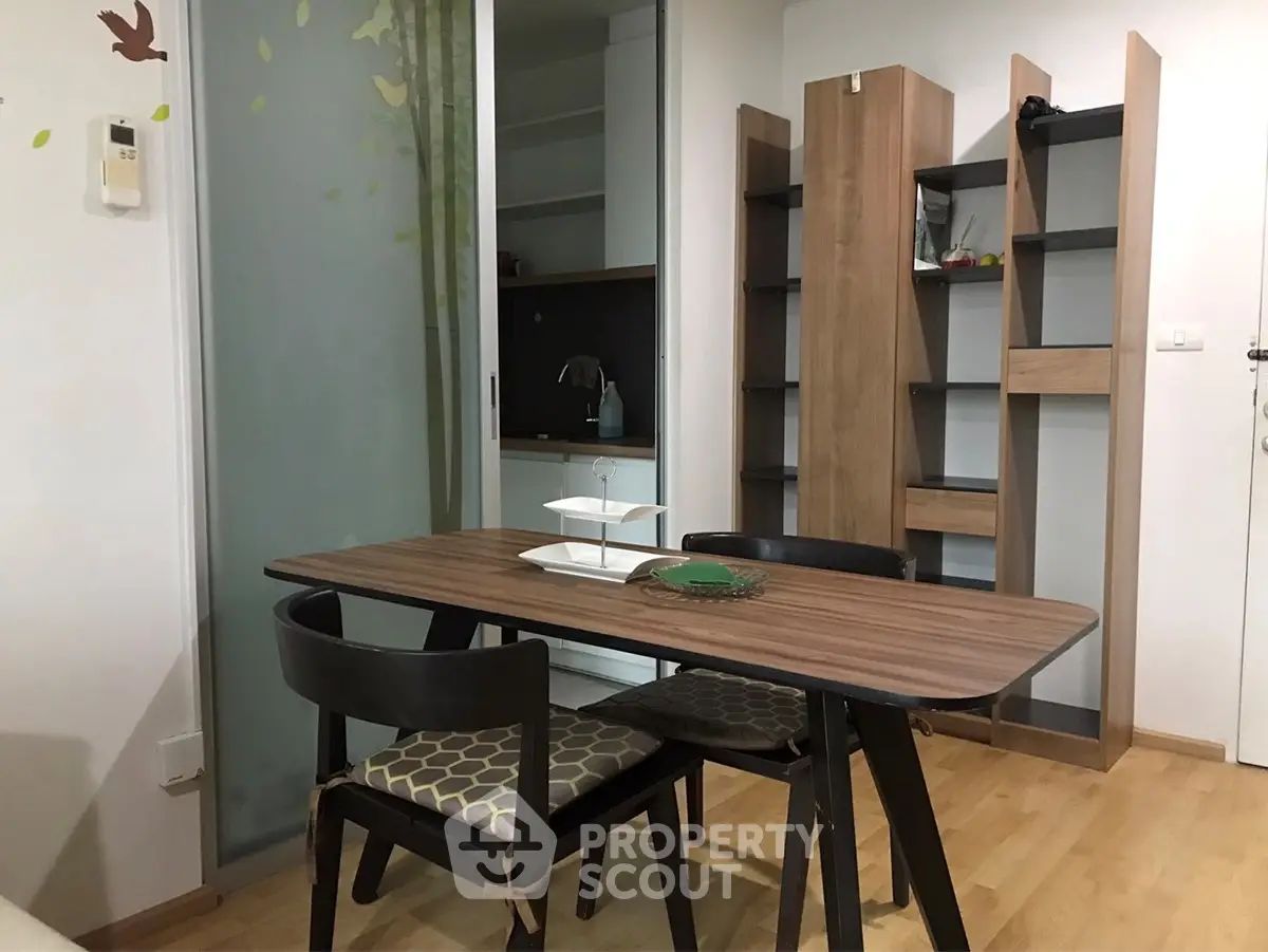 Modern dining area with wooden table and chairs, adjacent to a compact kitchen space.