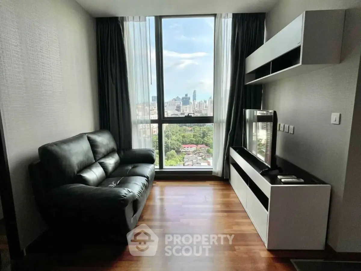 Modern living room with city view, featuring sleek furniture and large window.