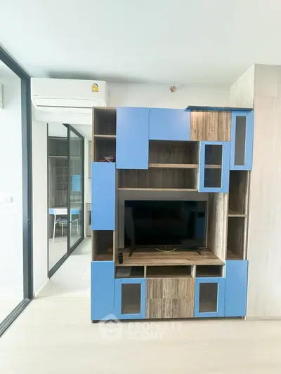 Modern living room with stylish blue and wood entertainment center and glass sliding doors.