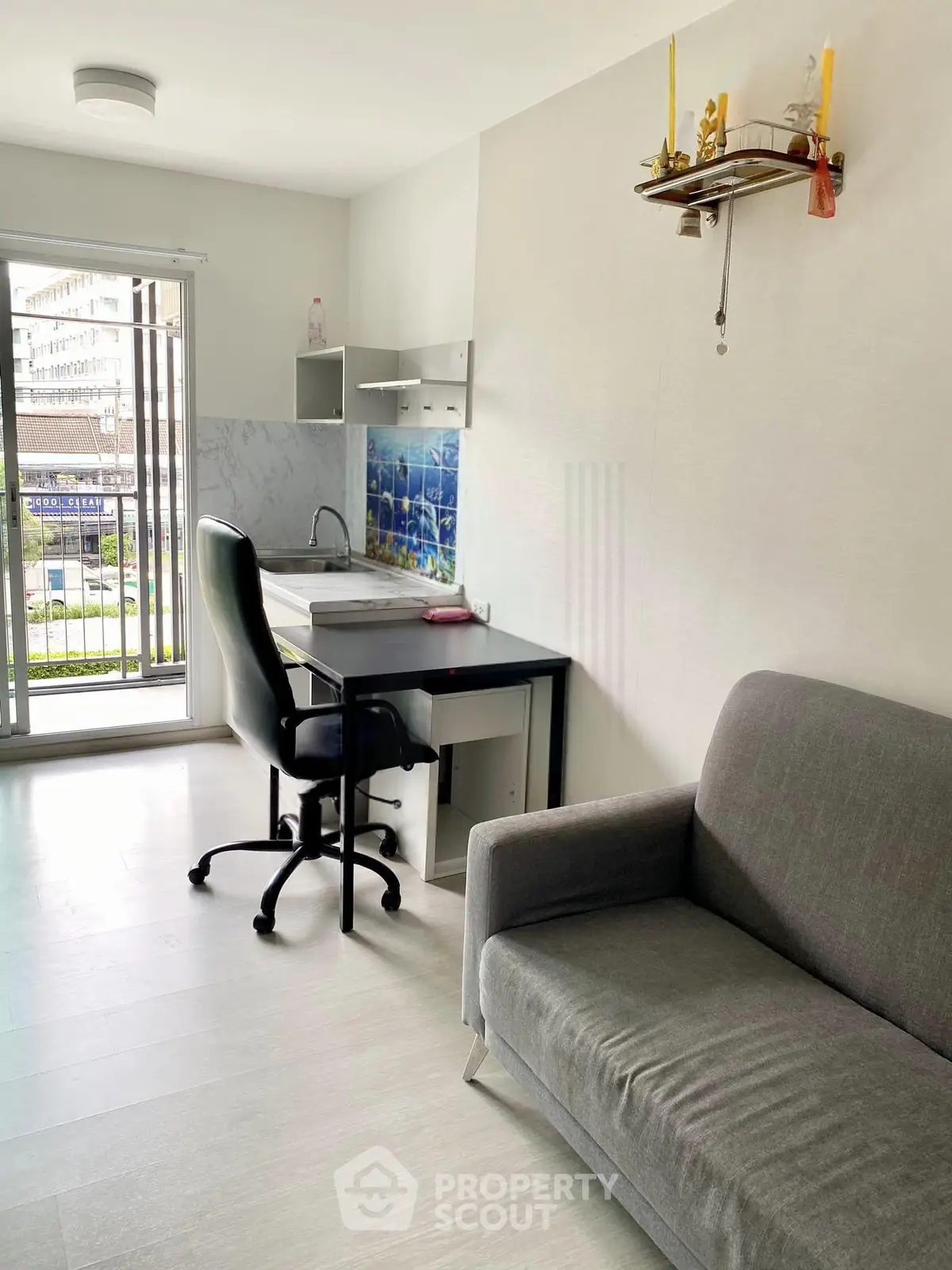 Modern studio apartment with compact kitchen and cozy living area, featuring a balcony view.