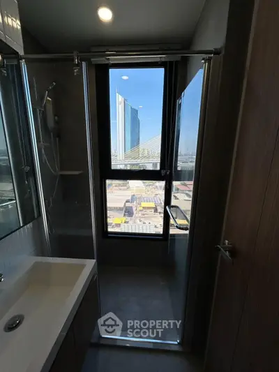 Modern bathroom with city view, featuring sleek shower and bathtub in high-rise apartment.