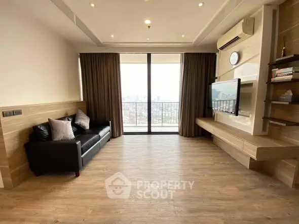 Spacious modern living room with city view, wooden flooring, and sleek entertainment setup.