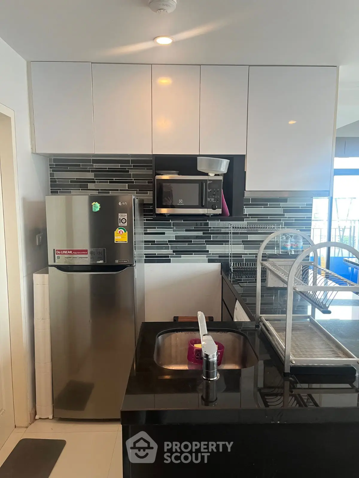 Modern kitchen with sleek black countertops and stainless steel appliances in a stylish apartment.