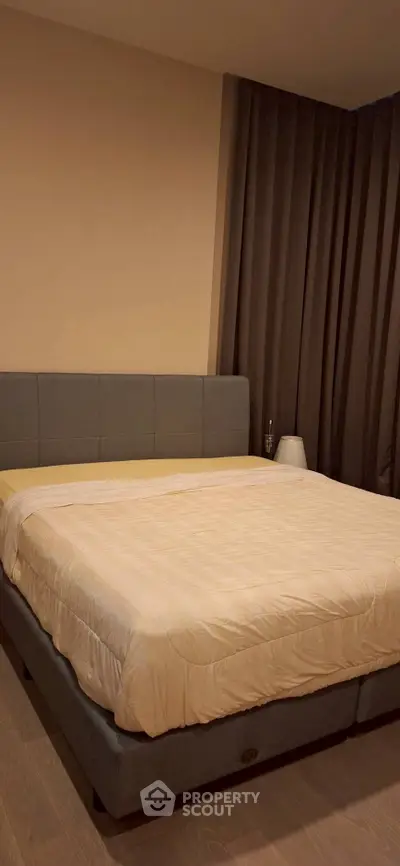 Spacious bedroom with elegant decor and cozy ambiance, featuring a large comfortable bed and stylish curtains.
