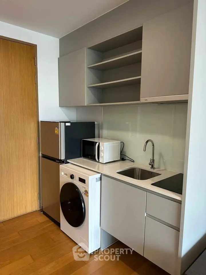 Modern compact kitchen with appliances including washing machine, microwave, and fridge in sleek design.