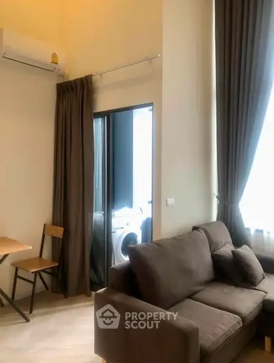 Modern living room with cozy sofa and dining area, featuring a washing machine in the background.