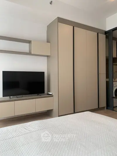 Modern bedroom with sleek wardrobe and mounted TV in stylish apartment.