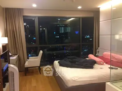 Luxurious bedroom with city view, modern furnishings, and floor-to-ceiling windows.